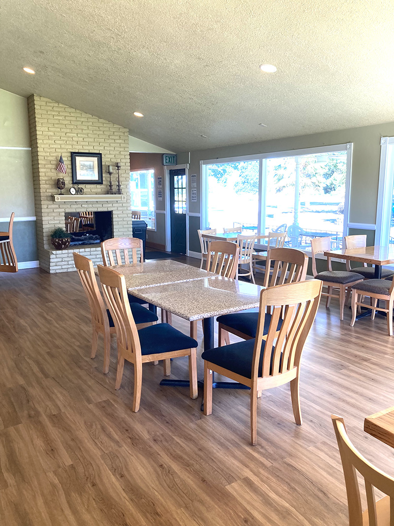 restaurant with wood floors, tables, and chairs as well as tall windows to the golf course